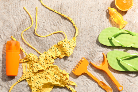 Composition with swimsuit, flip-flops and plastic toys on beach sandの写真素材
