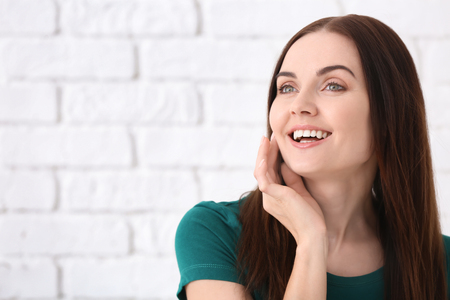 Beautiful young woman with healthy teeth on brick wall backgroundの写真素材