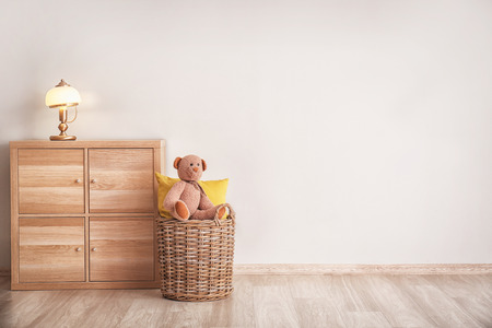 Cabinet with lamp and wicker basket near light wallの写真素材