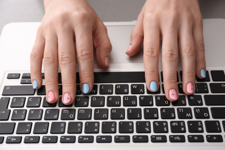 Woman with stylish color nails using laptop, closeupの写真素材