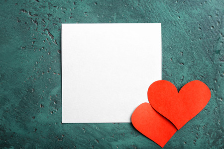 Blank card with paper hearts on green background