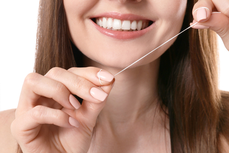 Young woman flossing her teeth on white backgroundの写真素材