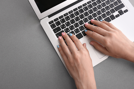 Woman with stylish color nails using laptop on table, closeupの写真素材