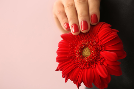 Young woman with beautiful manicure and flower on color background, closeupの写真素材