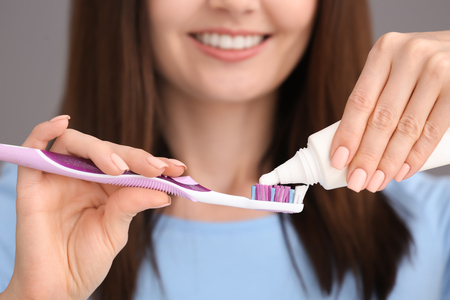 Young woman squeezing toothpaste on brush, closeupの写真素材