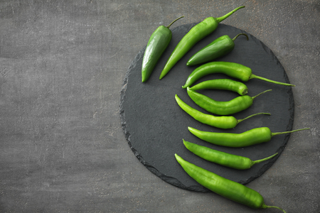 Slate plate with fresh chili peppers on grey textured backgroundの写真素材