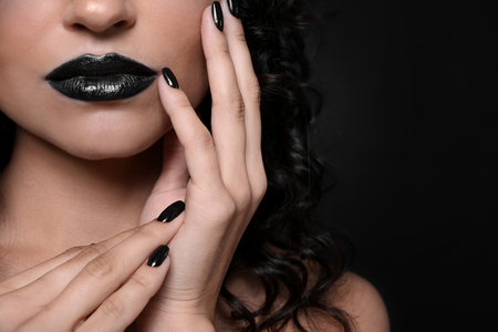 Fashionable young woman with black manicure on dark background, closeupの写真素材
