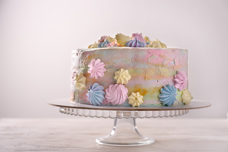 Stand with delicious birthday cake on table against light backgroundの写真素材