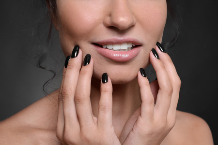 Fashionable young woman with black manicure on dark background, closeupの写真素材