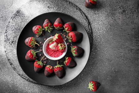 Plate with tasty chocolate dipped strawberries on tableの写真素材