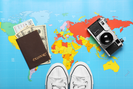 Composition with photo camera, gumshoes and passport on world map. Travel planning conceptの写真素材