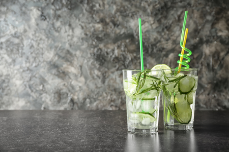 Fresh drink with sliced cucumber and rosemary in glasses on tableの写真素材