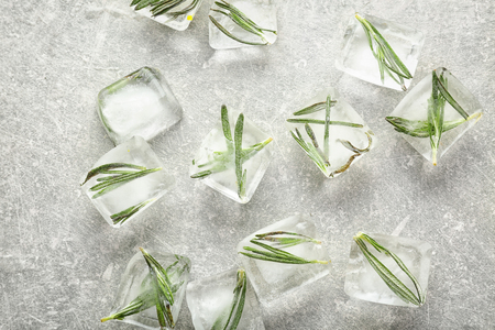 Rosemary frozen in ice cubes on light grey backgroundの写真素材