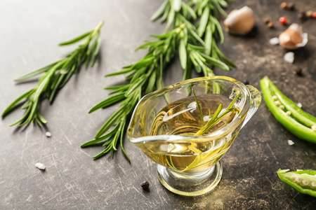 Gravy boat with oil and fresh rosemary on grey backgroundの写真素材