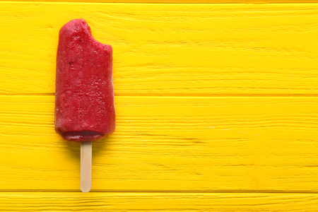 Delicious strawberry ice-cream on stick on color wooden backgroundの写真素材