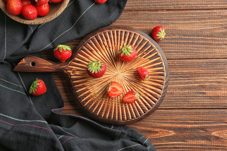 Wooden board with sweet ripe strawberries on tableの写真素材
