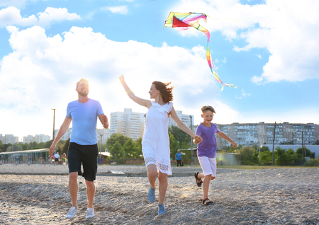 Happy family with kite on beachの写真素材