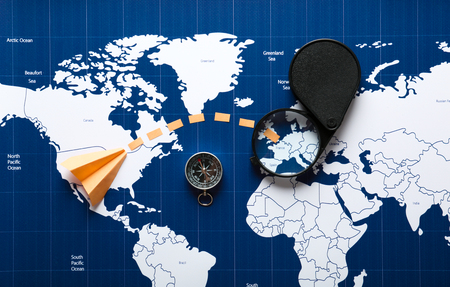 Creative composition with compass and designated route on world map