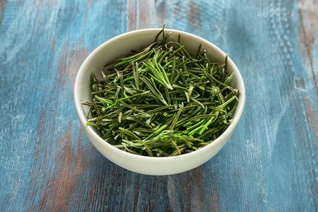 Bowl with rosemary on color wooden backgroundの写真素材