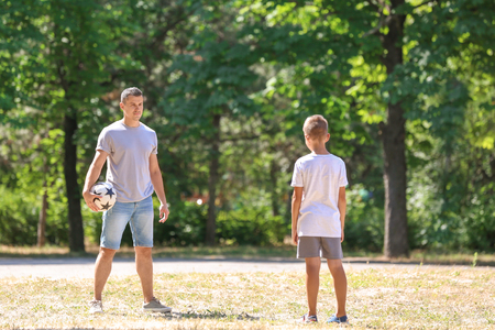 Little boy with his dad playing football outdoorsの写真素材