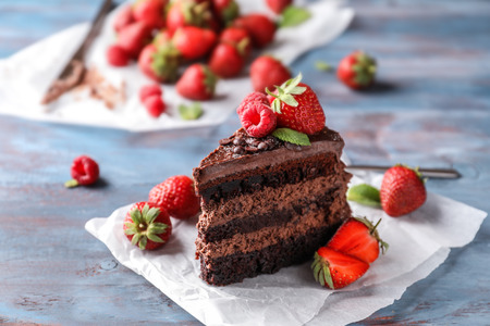 Piece of delicious chocolate cake with berries on wooden tableの写真素材