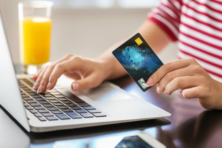 Young woman shopping online with credit card and laptop in cafe, closeupの写真素材