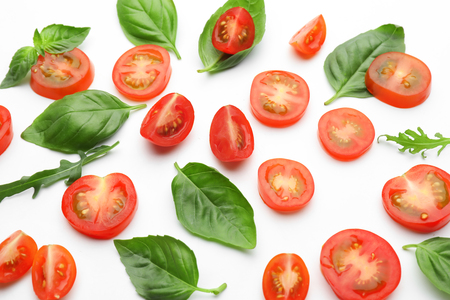 Sliced tomatoes with fresh herbs on white backgroundの写真素材