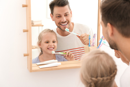 Little girl and her father brushing teeth in bathroomの写真素材