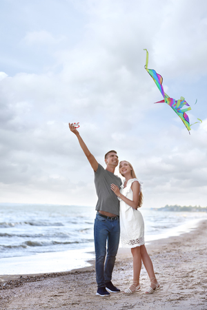 Happy young couple flying kite near seaの写真素材