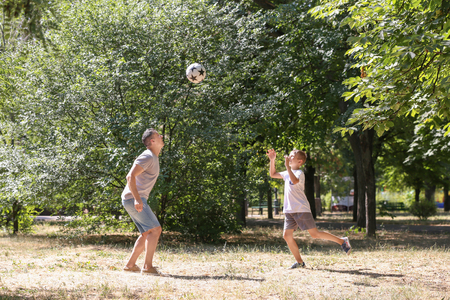 Little boy with his dad playing football outdoorsの写真素材