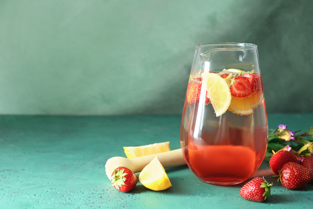 Tasty natural lemonade with strawberries in glass jug on tableの写真素材