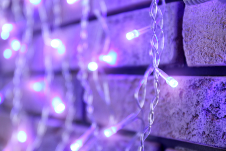 Beautiful bright Christmas garland near brick wall, closeupの写真素材