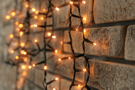 Beautiful bright Christmas garland near brick wall, closeupの写真素材