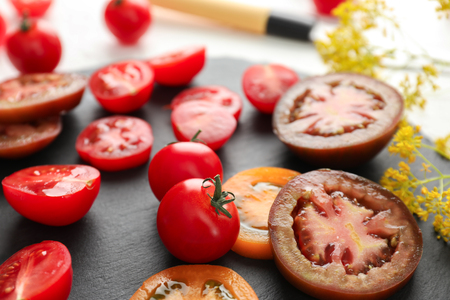Different sliced tomatoes on slate plate, closeupの写真素材