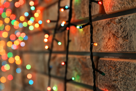 Beautiful bright Christmas garland near brick wall, closeupの写真素材