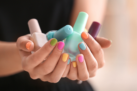 Young woman with colorful manicure holding bottles of nail polishes, closeupの写真素材