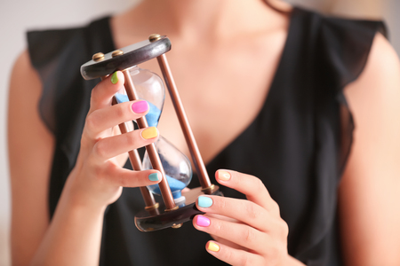 Young woman with colorful manicure holding hourglass, closeupの写真素材