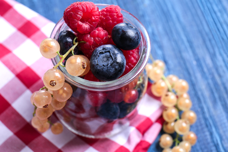Glass jar with different ripe berries on wooden table, closeupの写真素材