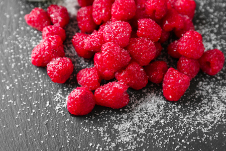 Delicious fresh ripe raspberries with sugar on slate plateの写真素材