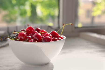 Bowl with tasty ripe cherries on windowsillの写真素材