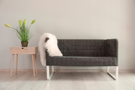 Comfortable sofa with table near light wall in interior of living roomの写真素材