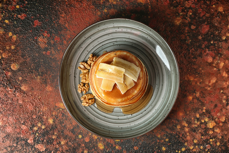 Tasty pancakes with walnuts and sliced banana on plateの写真素材