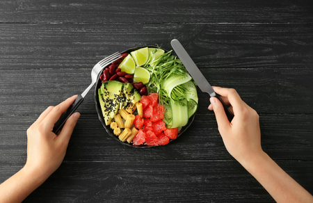 Woman eating delicious fresh salad at tableの写真素材