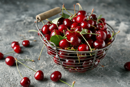 Basket with ripe cherries on grey textured backgroundの写真素材