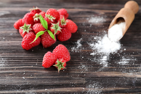 Ripe aromatic raspberries and scoop with sugar powder on wooden backgroundの写真素材