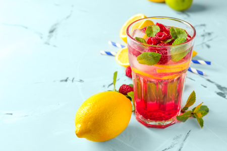 Glass of fresh raspberry mojito and ingredients on tableの写真素材