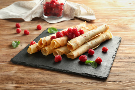 Slate plate with tasty pancakes and berries on wooden tableの写真素材