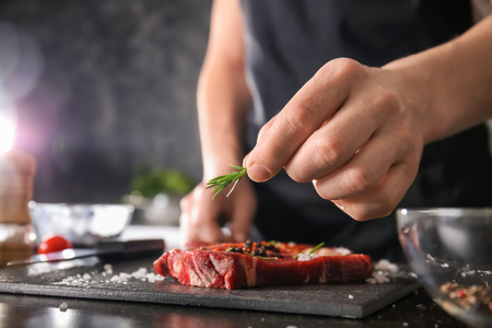 Man preparing meat in kitchen, closeupの写真素材