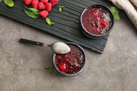 Bowls with sweet raspberry jam and fresh berries on table