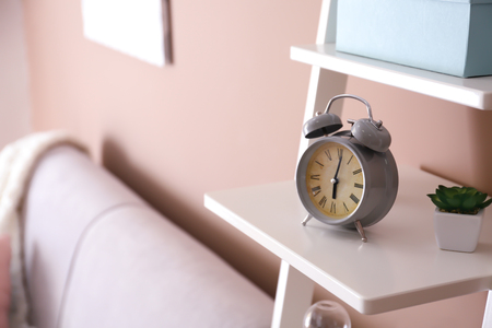 Alarm clock on shelf near color wallの写真素材
